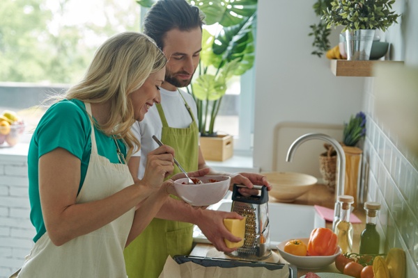 alegre pareja joven cocinando comida saludable